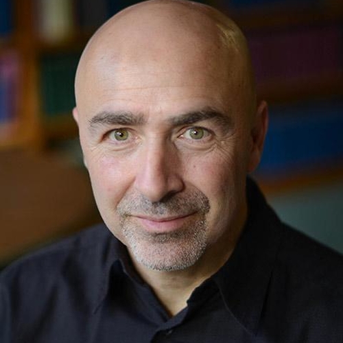 portrait of a bald man in black shirt looking directly into camera with kind but serious gaze