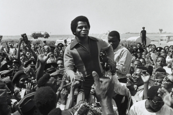 Singer James Brown surrounded by fans and media at airport in Nigeria