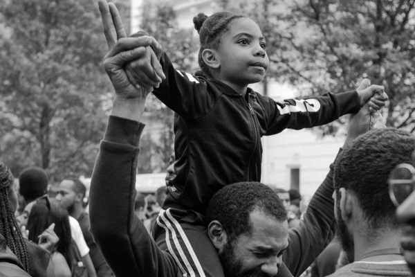 young Black girl on her father's shoulders looking ahead with hope