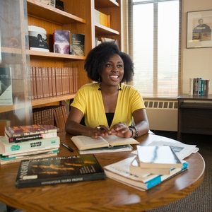 A young black woman at a table with books